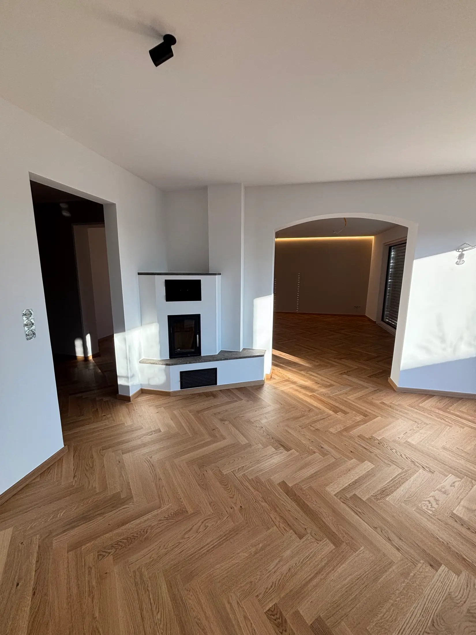 Renoviertes Wohnzimmer mit Kamin, Rundbogen und Fischgrätparkett nach Malerarbeiten