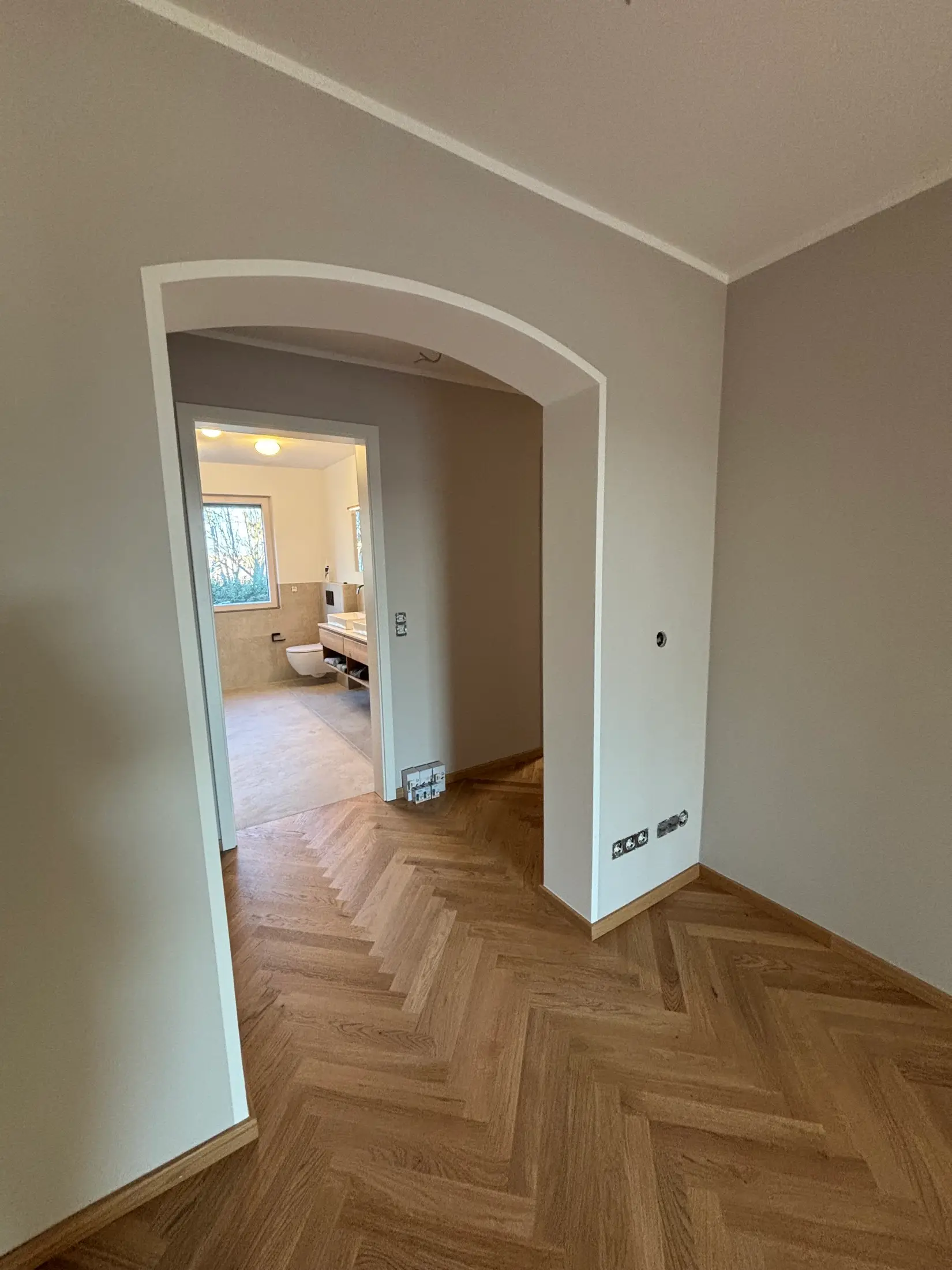 Renovierter Flur mit greige gestrichenen Wänden und weiß abgesetztem Rundbogen