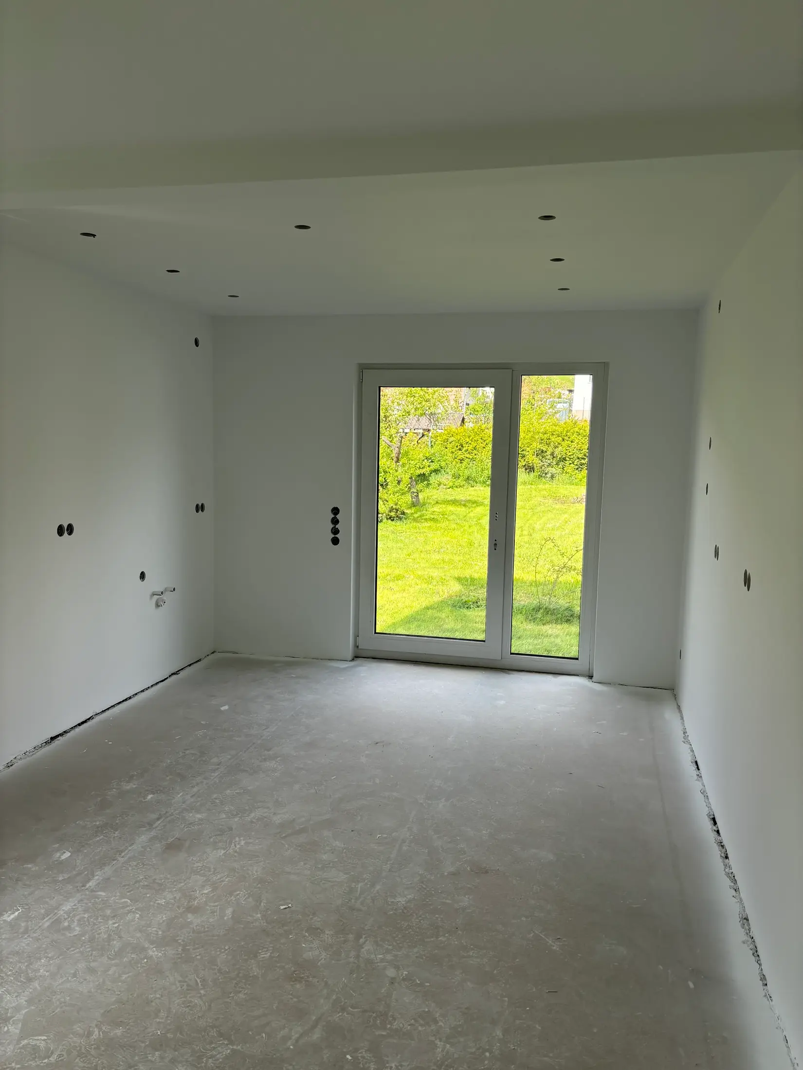 Großzügiger frisch gestrichener Wohnraum mit Spotdecke und großem Fenster