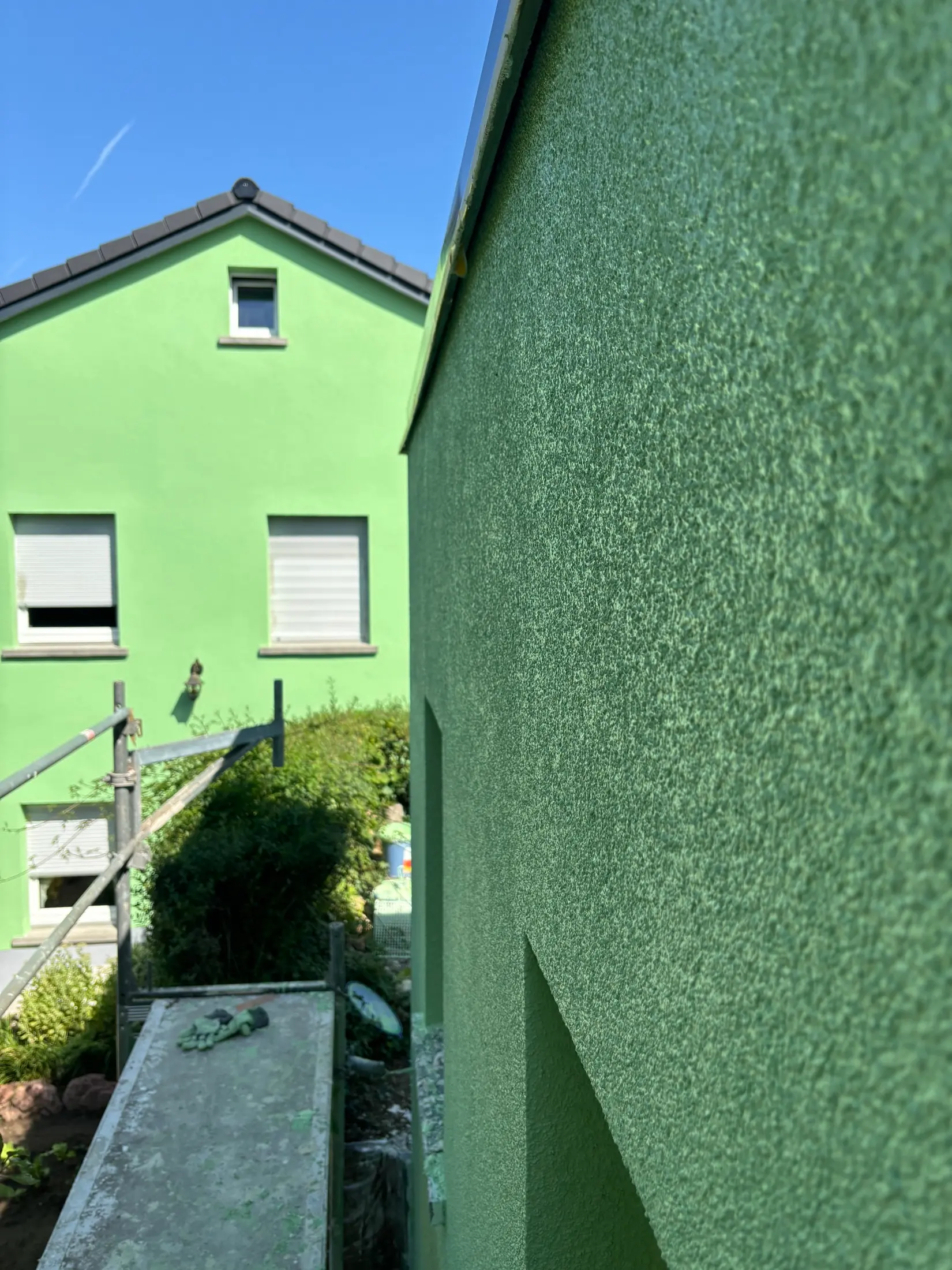 Frisch aufgetragener grüner Strukturputz an einer Hauswand, Putzarbeiten in Ausführung